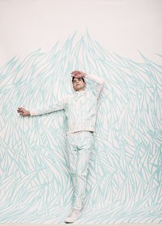 a man standing in front of a blue and white wall holding his hands on his head