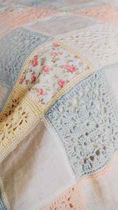 a crocheted blanket on top of a bed covered in white and pink flowers