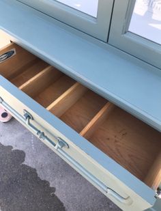 an open drawer on the side of a blue cabinet next to a gray carpeted floor