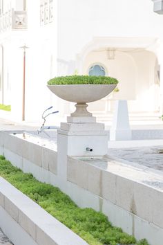 a planter sitting on the side of a building with grass growing out of it