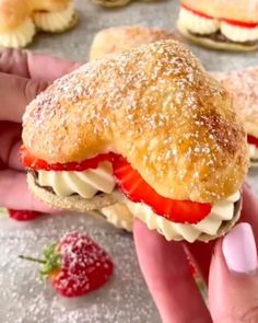 a person is holding a pastry with strawberries on it and other pastries in the background