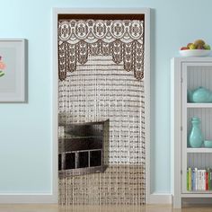 a living room with blue walls and a white bookcase next to a door that has an intricate lace design on it