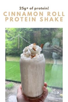 a person holding up a drink in front of a window with the caption 25 % of protein cinnamon roll protein shake