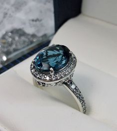 a ring with a blue topaz surrounded by white diamonds in a box on display