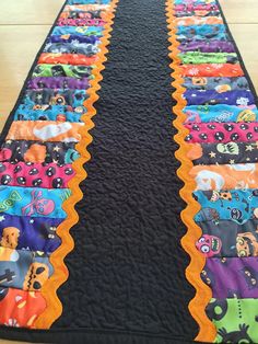 a table runner made out of fabric with colorful designs on it and black backings