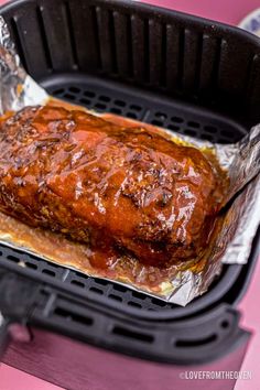 the meat is covered in barbecue sauce on top of tin foil and sits inside an air fryer