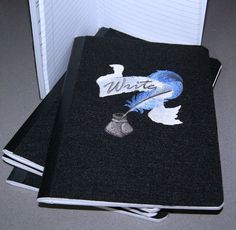 two black notebooks with blue writing on them