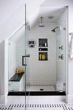 a white tiled bathroom with black and white floor tiles on the walls, shower head, and shelves