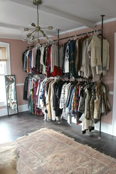 a room filled with lots of clothes hanging on the wall and a rug in front of it