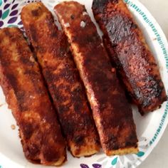 four pieces of meat sitting on top of a white and blue flowered paper plate