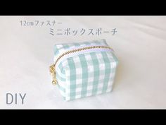 a small green and white checkered bag sitting on top of a bed with japanese writing