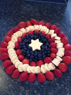 a cake decorated with strawberries, bananas and blueberries in the shape of a star