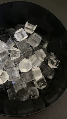 ice cubes in a black bowl on a table