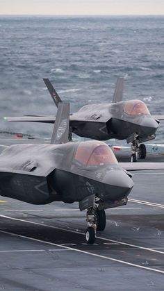 two fighter jets sitting on top of an aircraft carrier