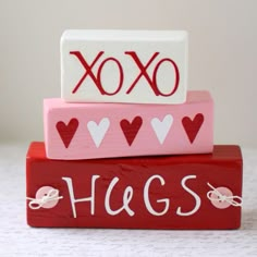 three wooden blocks that say hugs and xoxo on top of each other with hearts