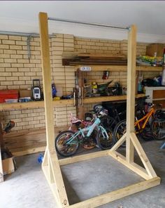 several bikes are parked in a garage next to some shelves with tools on them and one bike is propped up against the wall