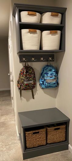 two baskets are hanging on the wall next to a coat rack with three bins