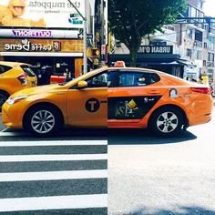 an orange taxi cab sitting in the middle of a crosswalk next to a building