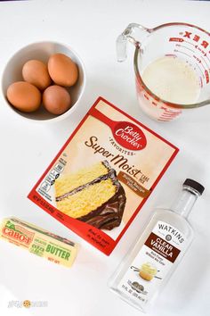 ingredients to make cake sitting on top of a white table next to a bowl of eggs