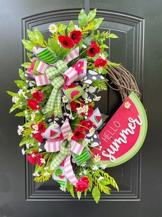 a wreath with red flowers and green leaves is hanging on the front door to welcome visitors