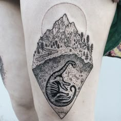 a woman's thigh with an image of a mountain and a dinosaur on it