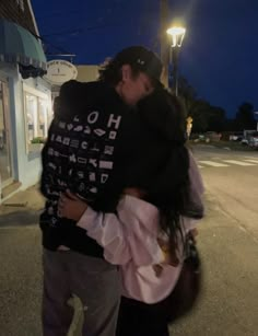 a man and woman hugging on the street at night