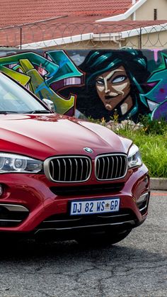 a red car parked in front of a graffiti covered wall