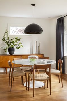 a dining room table with four chairs and a black light hanging from the ceiling over it