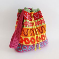 a colorful crocheted bag with tassels on the handles and drawstring