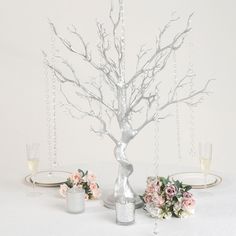 there is a silver tree with flowers and candles on the table next to each other