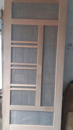 a wooden door with mesh coverings on the front and side panels, in an unfinished room