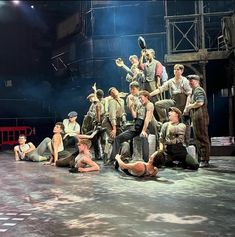 a group of people sitting on the ground in front of a stage with one person standing