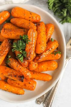 a white bowl filled with cooked carrots and parsley