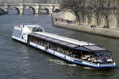 a tour boat traveling down the river in paris, with people sitting on it's seats