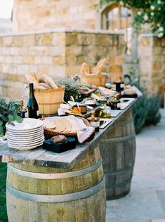 a table with plates and wine bottles on it next to some barrels filled with food