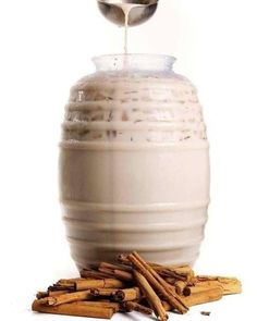 an image of cinnamon sticks being poured into a cream colored jar with cinnamon sticks on the side