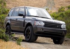 the land rover is driving on a dirt road