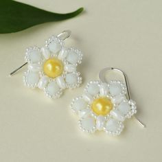 Our pearl flower earrings feature a cheerful, yellow pearl surrounded by over 150 white beads hand-woven into an intricate flower pattern.  The beaded flower dangles from sterling silver filled earrings that add a touch of sparkle.  The nature inspired jewelry will effortlessly enhance your style and add a pop of color to your summer wardrobe.  Embrace the beauty of nature with our lightweight, handmade earrings.  FIT:  The beaded flower is ¾ of an inch in diameter and the drop is roughly 1 inch White Beaded Pearl Earrings, White Sterling Silver Dangle Flower Earrings, Handmade White Sterling Silver Flower Earrings, White Flower Shaped Sterling Silver Earrings, White Flower-shaped Sterling Silver Earrings, White Flower Sterling Silver Earrings, White Sterling Silver Flower Earrings, Elegant White Flower Shaped Beaded Earrings, Handmade Flower Pearl Earrings