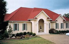 a white house with red roof and green shutters on the front door is shown