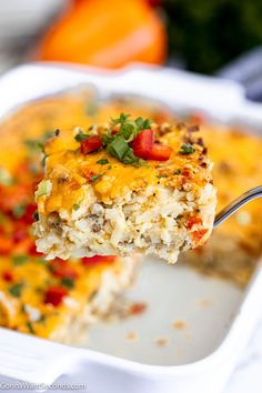 a close up of a piece of casserole on a fork in a white dish