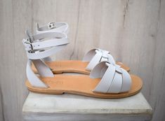 Handmade White Ankle Strap Sandals, Adjustable White Sandals For Festivals, Handmade White Sandals For Spring, White Handmade Leather Sandals, Handmade White Leather Sandals, Natural Color T-strap Sandals For Summer Beach, White Bohemian Adjustable Sandals, White Adjustable Bohemian Sandals, Casual Natural Barefoot Sandals For Summer