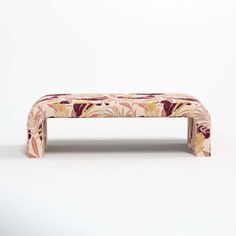 an upholstered bench is shown against a white background, with floral designs on it