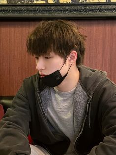 a young man wearing a black mask sitting at a table