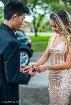 a young man and woman exchanging rings in front of a parked car on the street