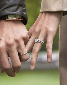 two people holding hands with wedding rings on their fingers, one is wearing a ring and the other has an engagement band