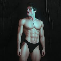 a man with no shirt on wearing a black thong and without his shirt is standing in front of a dark background