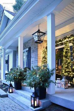 front porch decorated for christmas with potted plants and lanterns