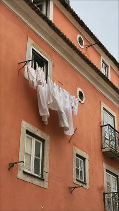 clothes hanging out to dry in front of an orange building with two balconies