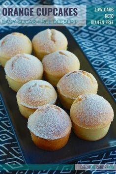 orange cupcakes on a black plate with powdered sugar