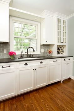 a kitchen with white cabinets and black counter tops